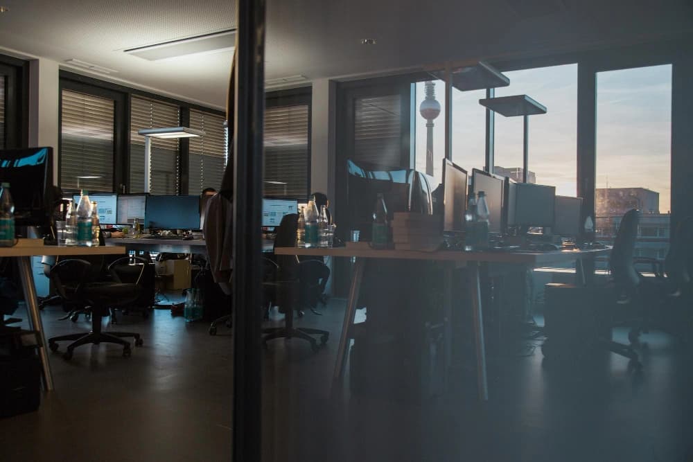 Open-plan office space featuring desks, monitors, and city views, representing MS Kapital’s commitment to innovation and teamwork.