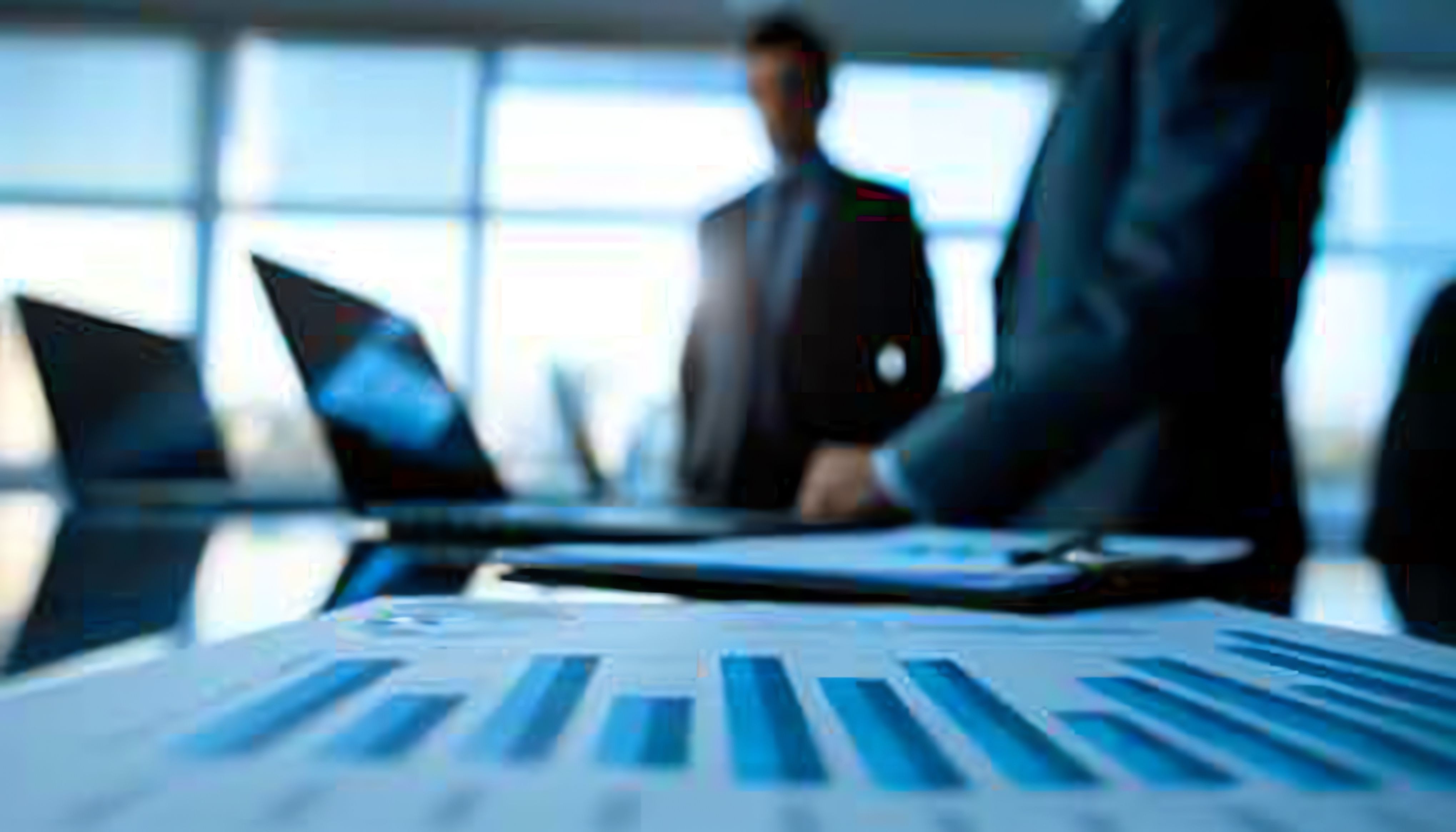 Business professionals reviewing due diligence data on a laptop with financial charts