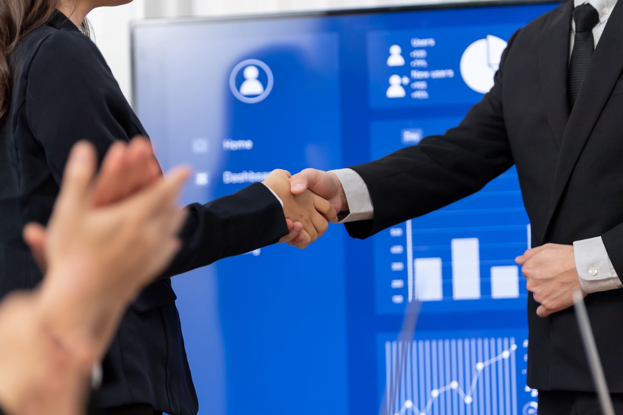 Executives shaking hands following successful late-stage M&A negotiations